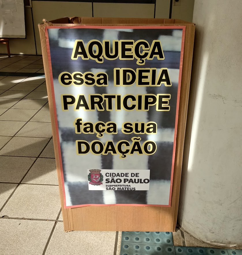 Caixa na entrada da Subprefeitura São Mateus com os dizeres: "Aqueça essa ideia. Participe, faça sua doação".